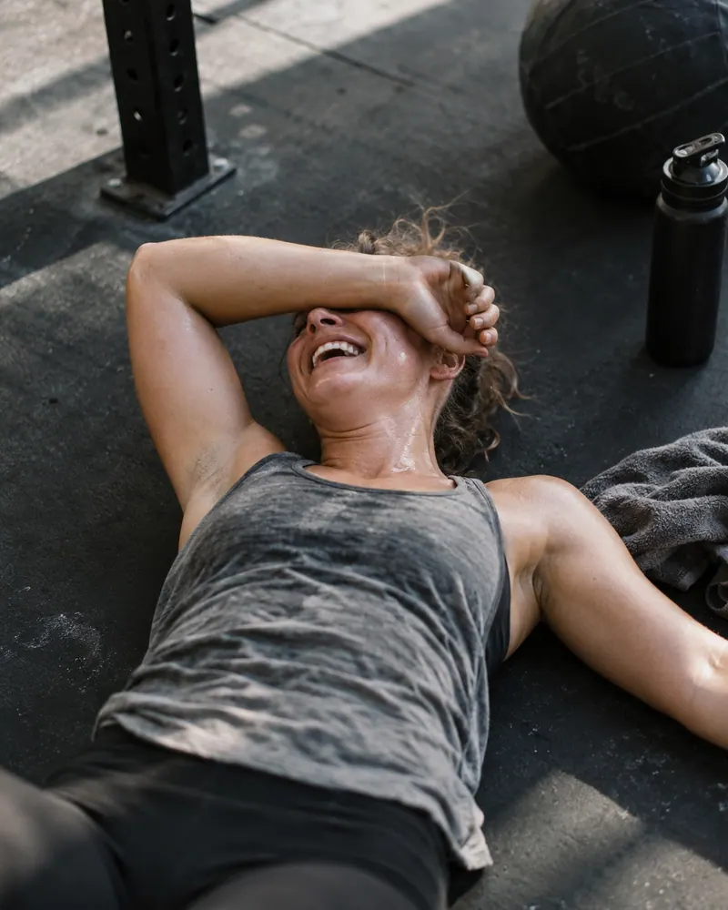 A tired, smiling person sitting on the floor after training.